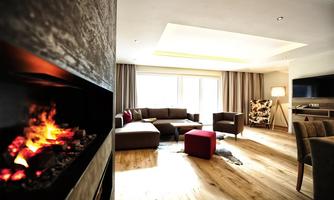 A modern living room with a cozy fireplace and large windows that let in plenty of light. The decor is stylish with a comfortable seating area and warm wooden floors.