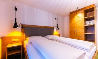 A cozy bedroom with two single beds. The walls are bright and the lighting creates a warm atmosphere.