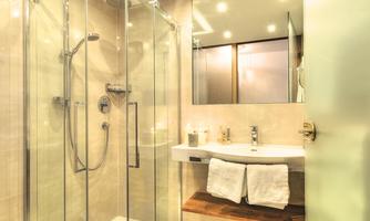 A modern bathroom with a glass shower and an elegant sink shelf. The room lighting is bright and inviting.