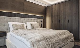 A modern bedroom with a large bed and a cozy bedding. The walls are in warm wood tones, and an elegant wardrobe completes the space.