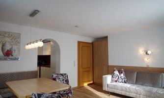 A modern living room with a comfortable sofa and a dining table. The walls are bright and there is a nice light accent.