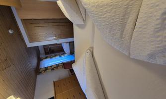 A cozy bedroom with two beds and light wood interior. The room is well lit and has modern furniture.