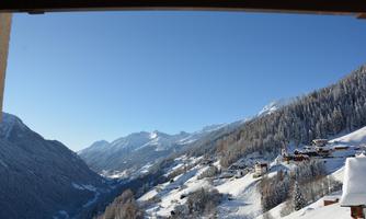 A winter mountain landscape with snow-covered hills and mountains. The clear blue sky completes the tranquil scene.