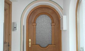 A beautiful wooden door with a glass insert in a bright entrance area. The room is designed to be friendly and inviting.