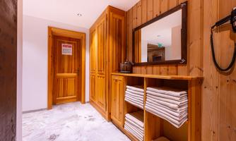 A stylish hallway with wooden walls and a wooden dresser. Clean towels are laid out on the dresser, and a mirror reflects the warm decor.