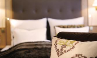 A cozy bedroom with a large bed and soft pillows. The decorative cushions add an elegant touch to the room.
