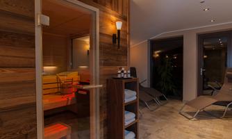 A relaxing wellness area with a sauna and loungers. Warm wooden tones and soft lighting create a calming atmosphere.