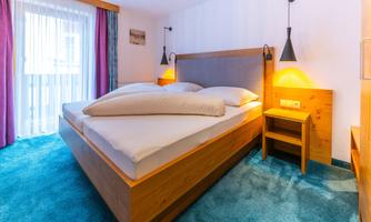 A modern bedroom with a large double bed and wooden details. Soft light creates a cozy atmosphere.