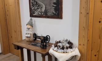 A rustic entrance area with a wooden table and an old sewing machine. A black-and-white picture of a mountain landscape hangs on the wall.