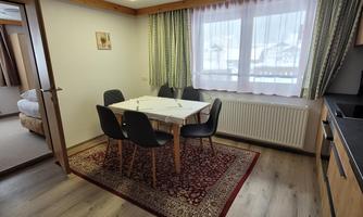 A bright dining area with a table and four chairs. Large windows let in a lot of light.