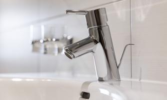 A modern chrome faucet above a sink. The elegant shape and shiny finish give the bathroom a stylish look.