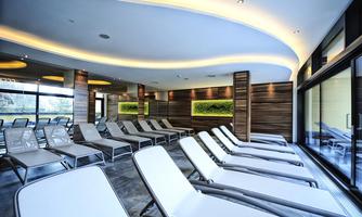 A modern relaxation room with comfortable loungers and soft lighting. Large windows offer a view of nature and create a relaxing atmosphere.