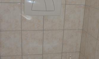 A simple bathroom with a white toilet and tiled walls. The space feels clean and well-maintained.