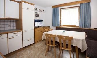 A cozy kitchen with wooden cabinets and a dining area. A window provides pleasant light in the room.