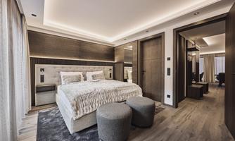 A modern bedroom with a large bed and soft pillows. The walls are painted in warm tones and the room has a cozy atmosphere.