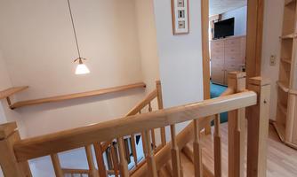 A staircase with a wooden railing and a bright entrance. In the background, there is an open door to another room.