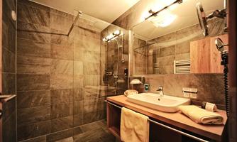 A modern bathroom with a glass shower and an elegant sink installation. The walls are tiled in elegant shades of gray.