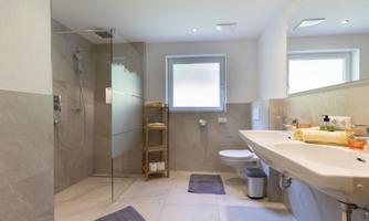 A modern bathroom with a glass shower and a large sink. Bright colors and practical shelves create a friendly atmosphere.