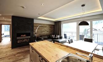 A modern apartment with an open living area and large windows. The space features a cozy sitting area, a dining table, and a modern fireplace.