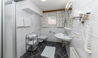 A modern bathroom with white tiles and a large mirror. Towels and toiletries are neatly placed.