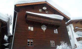 A cozy wooden house with a snow-covered roof.  
Surrounded by a winter landscape with snow.