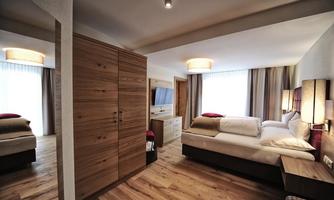 A cozy bedroom with wooden flooring and modern furniture. There is a large window that lets in natural light.
