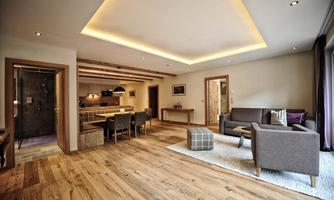 A modern living room with hardwood floors and stylish furniture. The open kitchen and dining area give the space an inviting atmosphere.