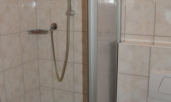A modern shower with a glass partition and tiles. The space is bright and tidy.