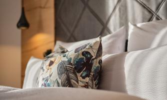 A cozy bedroom with soft pillows and a decorative cushion. Gentle light and elegant textures create a relaxed atmosphere.