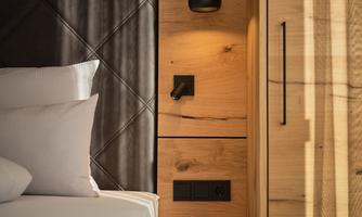A modern bedroom with a comfortable bed and an elegant wooden design. A stylish lamp hangs on the wall.
