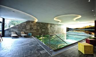 A modern swimming pool with elegant tiles and soft lighting. In the background, relaxing views of nature can be seen.