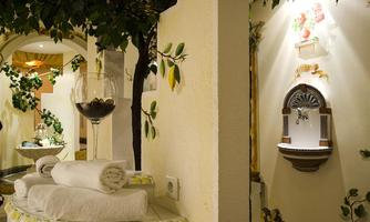 An elegant wellness area with white towels and a wine glass. In the background, decorative plants and a stylish wall fountain can be seen.