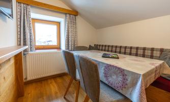 A cozy living area with a dining table and a windowsill. The room is bright and friendly, with a view outside.