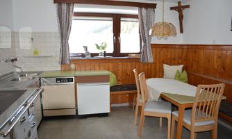 A cozy kitchen with wooden elements and a dining area. The window offers a view to the outside and the decor is functional and inviting.