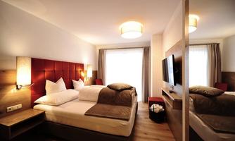 A modern hotel room with two beds and minimalist design. Large windows provide plenty of natural light and a relaxing atmosphere.