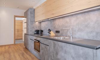 Modern kitchen with gray walls and wooden cabinets. There is a sink, an oven, and a coffee machine.