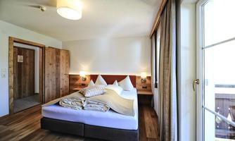 A bright bedroom with a large bed and hardwood floor. Large windows provide plenty of daylight.