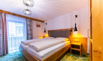 A cozy bedroom with a large double bed and modern lamps. The soft lighting creates an inviting atmosphere.