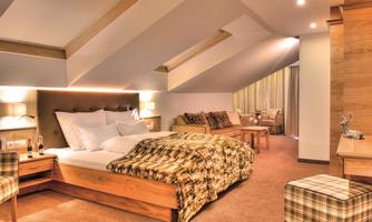 A cozy bedroom with a large bed and wooden details. The room has a warm atmosphere and a modern design.