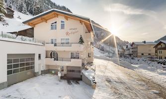 A cozy building in the snow with a sunny view of the mountains. The surroundings are calm and picturesque, perfect for a winter holiday.