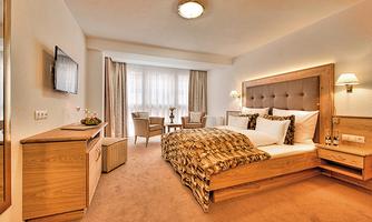 A modern bedroom with a comfortable bed and elegant wooden paneling. The room has large windows that provide plenty of natural light.