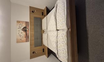 A modern bedroom with a double bed and cozy bedding. An artwork hangs on the wall, and the lighting is functional.