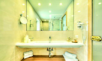 A modern bathroom with a large mirror and bright interior. The wooden surface and clean towels create an inviting atmosphere.