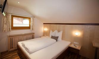 A cozy bedroom with two single beds and a bright decor. The window provides natural light and a pleasant atmosphere.