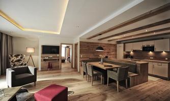 A modern and inviting living kitchen with wooden flooring and an open living area. The decor combines stylish furniture with warm colors and cozy lighting.