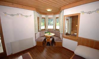 A cozy room with a round table and a seating area. Large windows provide plenty of natural light and an inviting atmosphere.