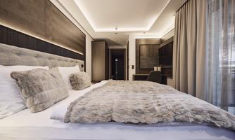 A modern bedroom with a cozy bed, surrounded by stylish wood design. The soft lighting creates a relaxed atmosphere.