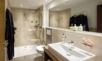 A modern bathroom with a shower and a large sink. The walls are painted in neutral tones, and there are toiletries on the sink.