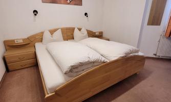 A cozy bedroom with a large wooden bed and two nightstands. On the wall hangs a picture of a boat.