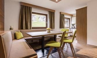 A modern dining room with a table and chairs in cheerful colors. Large windows offer a view of the surrounding landscape.